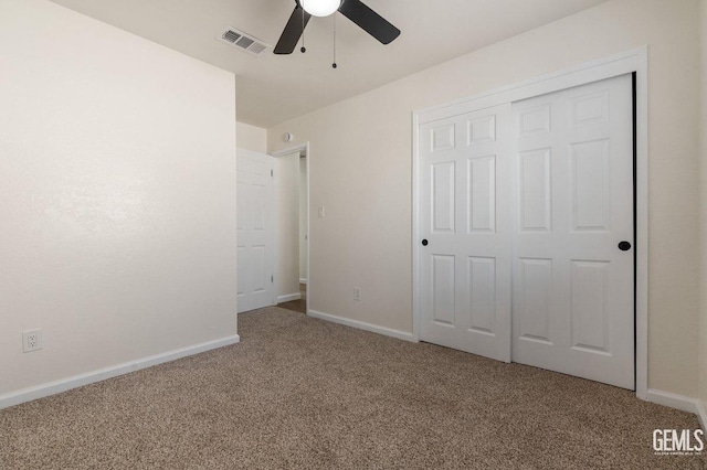 unfurnished bedroom featuring carpet, visible vents, a ceiling fan, a closet, and baseboards