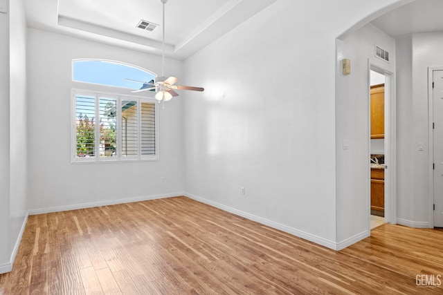 4207 Crystal Lake Dr, Bakersfield, CA 93313 - spare room with arched walkways, light wood-style floors, a ceiling fan, and a tray ceiling