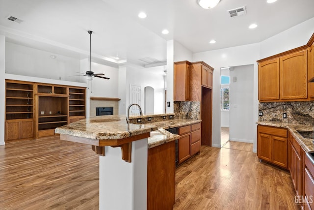 4207 Crystal Lake Dr, Bakersfield, CA 93313 - kitchen featuring a kitchen breakfast bar, a peninsula, backsplash, brown cabinets, and recessed lighting