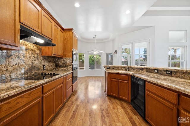 4207 Crystal Lake Dr, Bakersfield, CA 93313 - kitchen with black appliances, under cabinet range hood, light wood-style flooring, brown cabinets, and recessed lighting