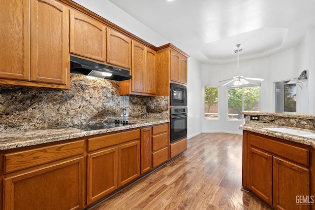 4207 Crystal Lake Dr, Bakersfield, CA 93313 - kitchen featuring black appliances, under cabinet range hood, a raised ceiling, backsplash, and light wood finished floors