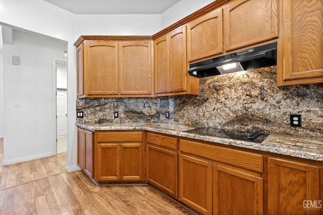 4207 Crystal Lake Dr, Bakersfield, CA 93313 - kitchen with under cabinet range hood, black electric stovetop, light wood finished floors, backsplash, and light stone counters