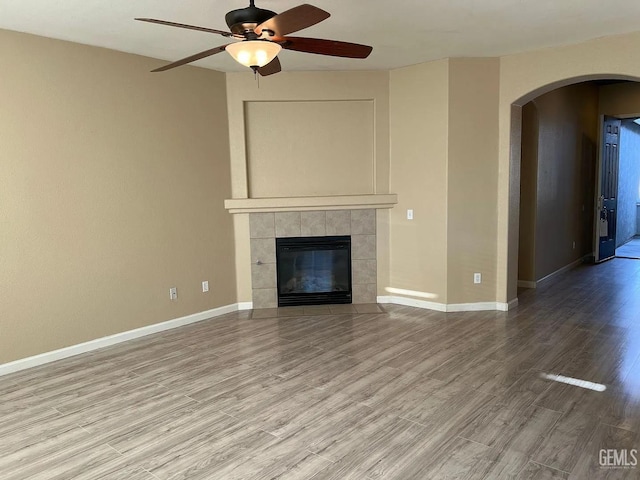 5413 Ridgecrest Ct, Bakersfield, CA 93313 - unfurnished living room with arched walkways, a ceiling fan, wood finished floors, and a tiled fireplace