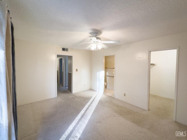 empty room featuring ceiling fan, a textured ceiling, and light colored carpet