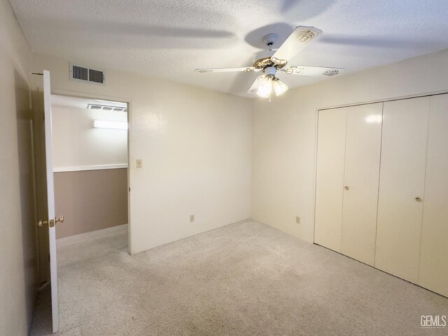 unfurnished bedroom featuring light carpet, a closet, ceiling fan, and a textured ceiling