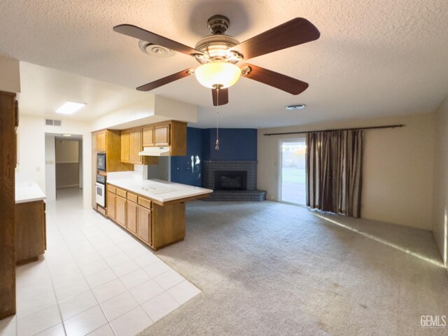 kitchen featuring kitchen peninsula, a brick fireplace, oven, black microwave, and a textured ceiling