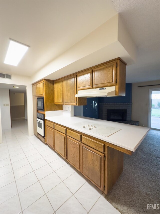 kitchen featuring light tile patterned floors, white appliances, and kitchen peninsula