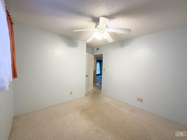 spare room with light carpet, ceiling fan, and a textured ceiling