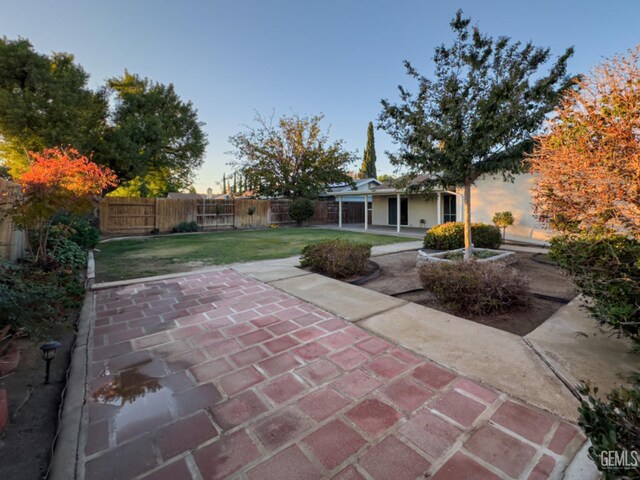 patio terrace at dusk featuring a yard