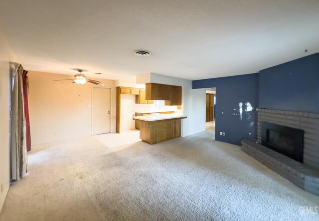 unfurnished living room featuring light carpet, ceiling fan, and a fireplace