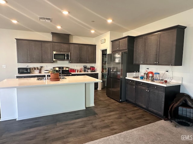 7410 Koyuk River St, Bakersfield, CA 93311 - kitchen with appliances with stainless steel finishes, light countertops, dark brown cabinetry, dark wood finished floors, and an island with sink