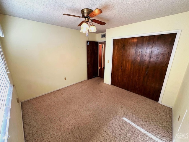 unfurnished bedroom with a closet, ceiling fan, a textured ceiling, and light carpet