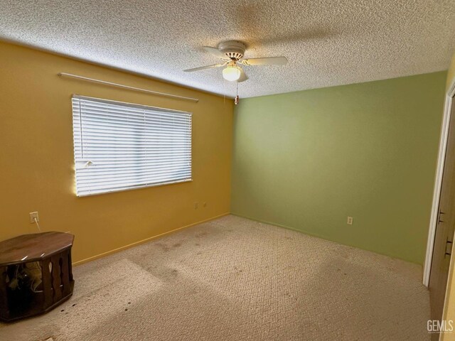 unfurnished bedroom with a textured ceiling, a closet, light colored carpet, and ceiling fan