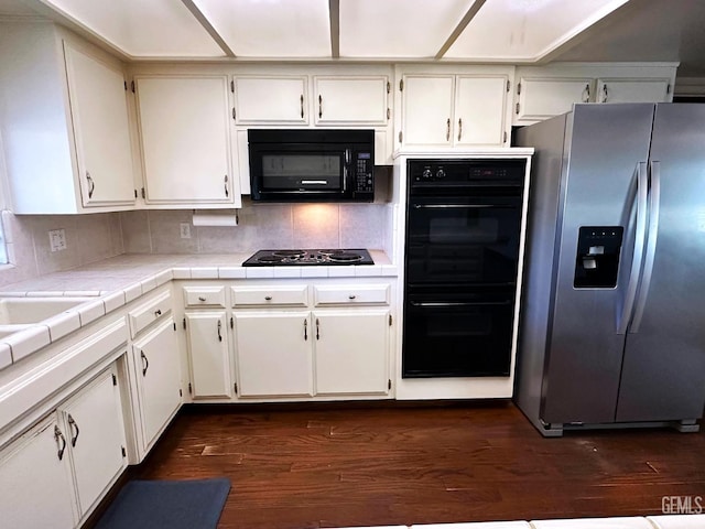 kitchen featuring black appliances, white cabinets, dark wood-type flooring, backsplash, and tile countertops