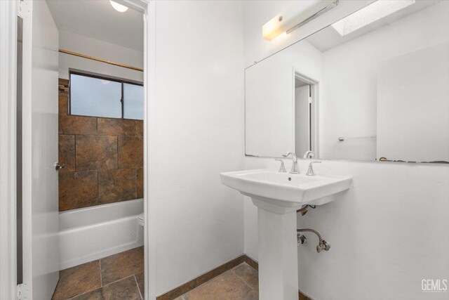 bathroom with toilet, tiled shower / bath, and a skylight