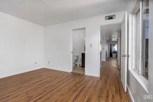 unfurnished room with a healthy amount of sunlight and dark wood-type flooring