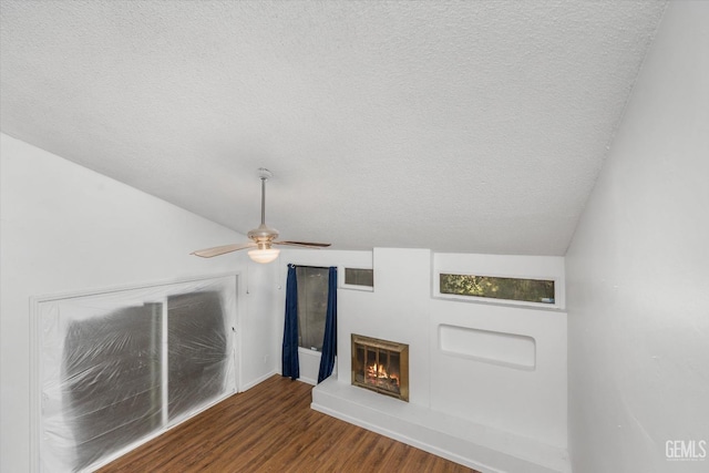 unfurnished living room featuring lofted ceiling, ceiling fan, a textured ceiling, and hardwood / wood-style flooring