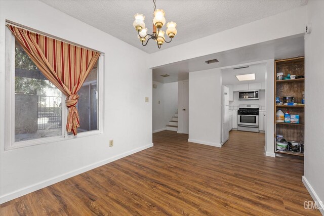 unfurnished dining area featuring dark hardwood / wood-style flooring, a textured ceiling, and a chandelier