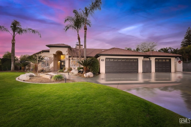 mediterranean / spanish-style house featuring driveway, an attached garage, a front lawn, and stucco siding