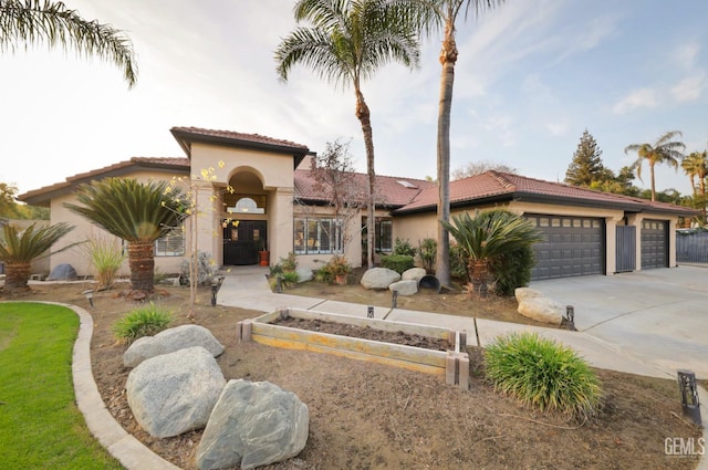 mediterranean / spanish-style house with driveway, a tile roof, a garage, and stucco siding