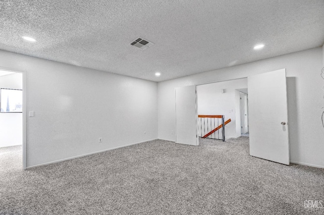 spare room featuring carpet, visible vents, a textured ceiling, and recessed lighting