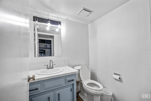 half bathroom with toilet, visible vents, and vanity