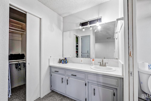 bathroom with a textured ceiling, toilet, and vanity