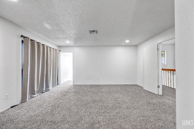 carpeted empty room with visible vents and a textured ceiling