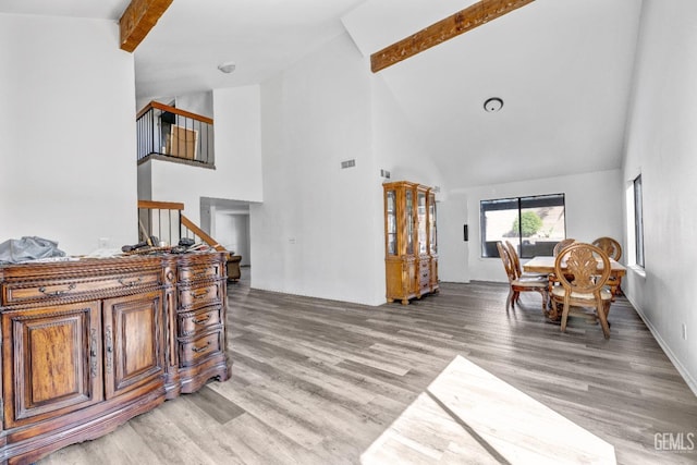 interior space with light wood-style floors, beamed ceiling, high vaulted ceiling, and stairs