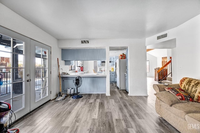 interior space featuring french doors, light countertops, visible vents, freestanding refrigerator, and a peninsula