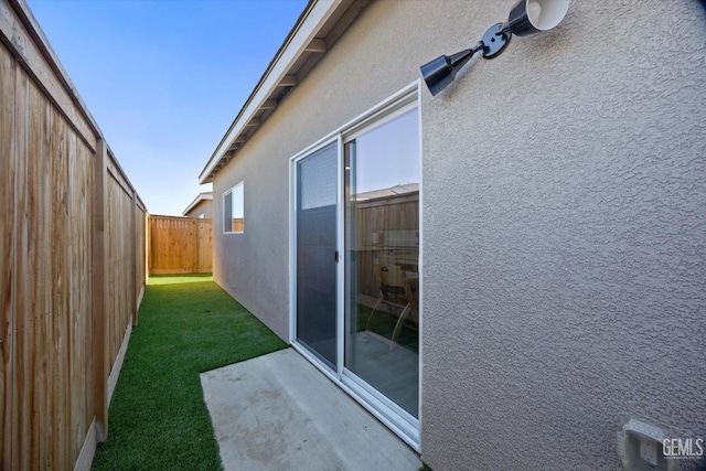 view of side of home with a patio area and a lawn