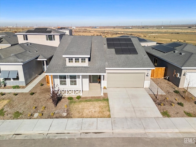 view of front of property featuring covered porch, a garage, and solar panels