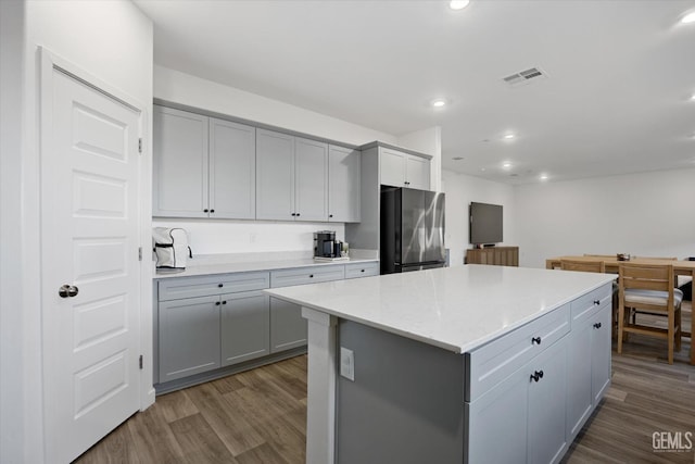 kitchen with gray cabinetry, dark hardwood / wood-style flooring, a kitchen island, and stainless steel refrigerator