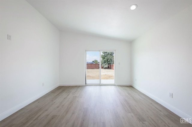 unfurnished room featuring lofted ceiling, wood finished floors, and baseboards