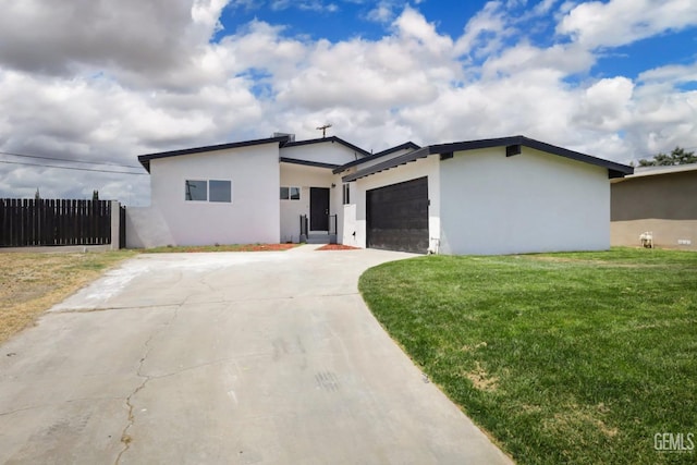 view of front of home with stucco siding, fence, a garage, driveway, and a front yard