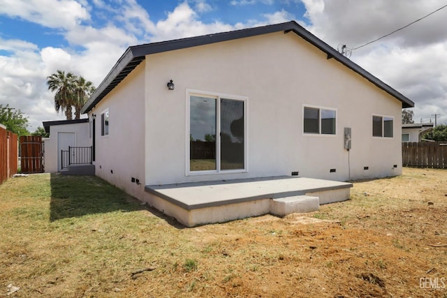 rear view of property featuring fence, a patio area, a lawn, crawl space, and stucco siding
