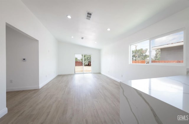 unfurnished living room featuring lofted ceiling, light wood-style floors, visible vents, baseboards, and recessed lighting