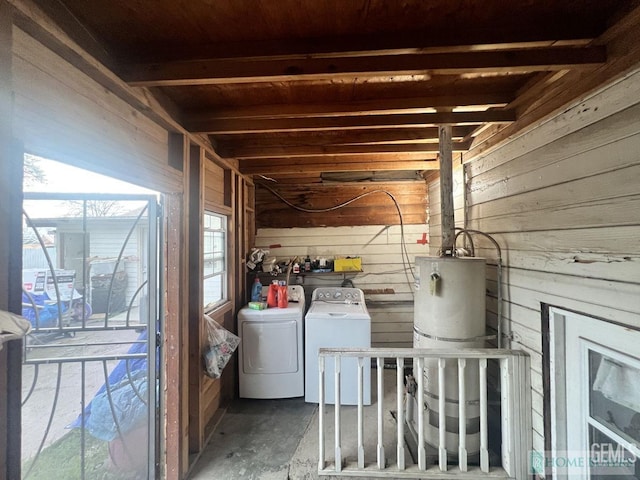 washroom with laundry area, strapped water heater, wooden walls, and washing machine and clothes dryer