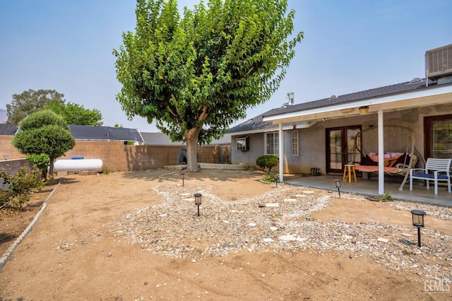 view of yard with a patio area, a fenced backyard, central AC, and french doors