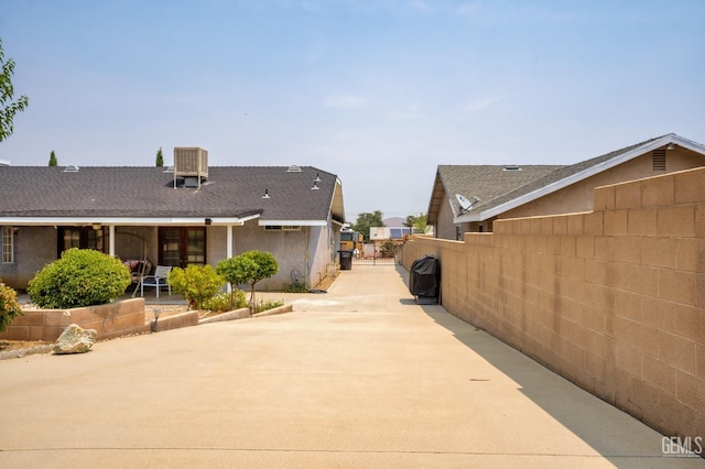 view of home's exterior featuring a patio, cooling unit, fence, concrete driveway, and a gate