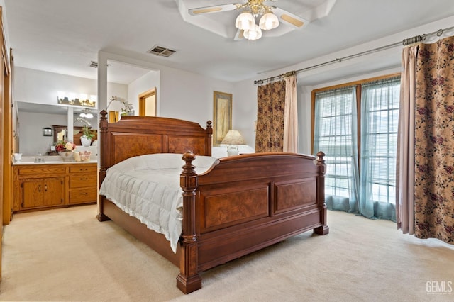 bedroom with light carpet, a ceiling fan, visible vents, and connected bathroom