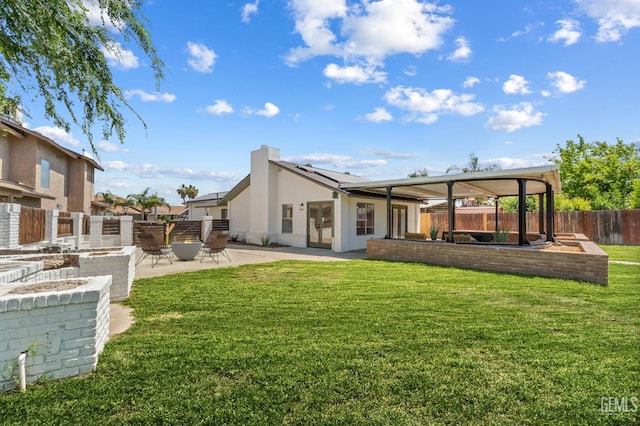 6201 Regina Way, Bakersfield, CA 93307 - back of property featuring an outdoor fire pit, a patio area, solar panels, a chimney, and stucco siding