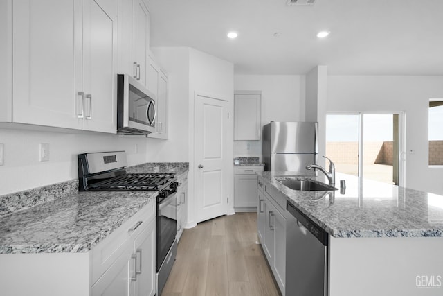 8401 Seth Alexander Way, Bakersfield, CA 93306 - kitchen with appliances with stainless steel finishes, light wood-style flooring, a center island with sink, recessed lighting, and light stone counters