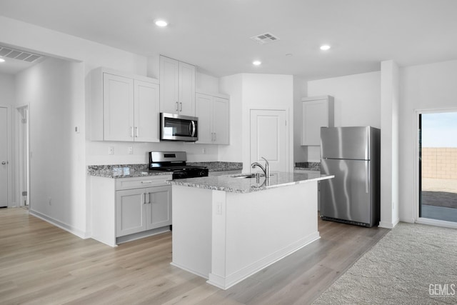 8401 Seth Alexander Way, Bakersfield, CA 93306 - kitchen featuring appliances with stainless steel finishes, light wood-type flooring, light stone countertops, an island with sink, and recessed lighting