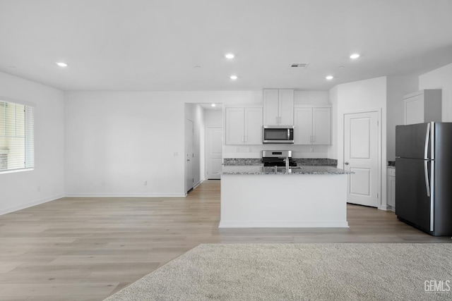8401 Seth Alexander Way, Bakersfield, CA 93306 - kitchen featuring stainless steel appliances, recessed lighting, light wood-style floors, an island with sink, and stone counters