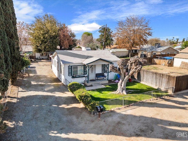 bungalow-style home featuring roof with shingles, a front lawn, and a fenced front yard