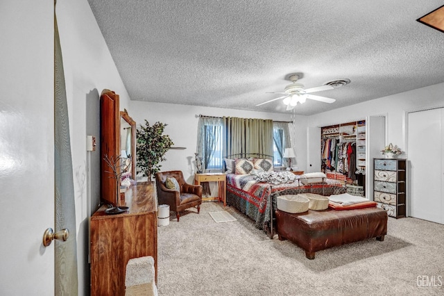 bedroom with ceiling fan, light colored carpet, and a textured ceiling