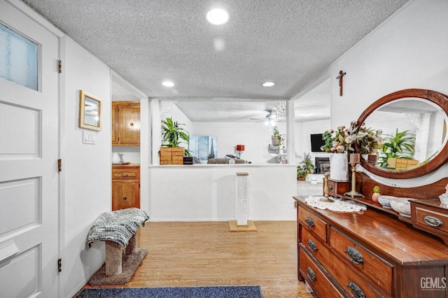 interior space with ceiling fan, light hardwood / wood-style floors, and a textured ceiling