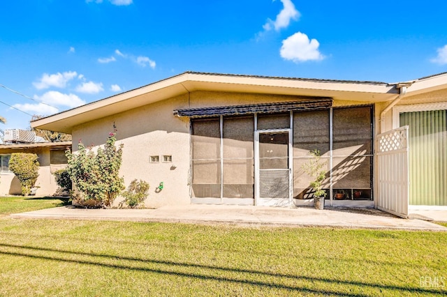 rear view of house featuring a sunroom and a lawn