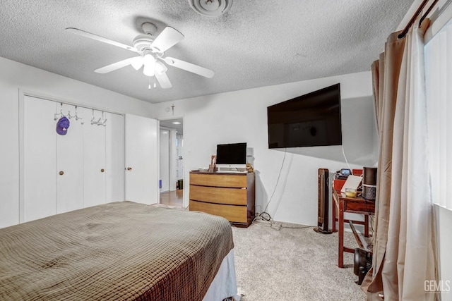 bedroom with ceiling fan, light colored carpet, a textured ceiling, and a closet